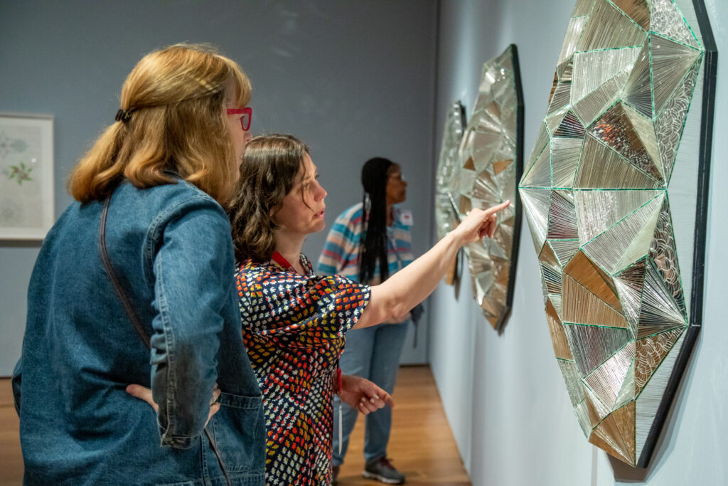 Two individuals looking and pointing at an artwork.