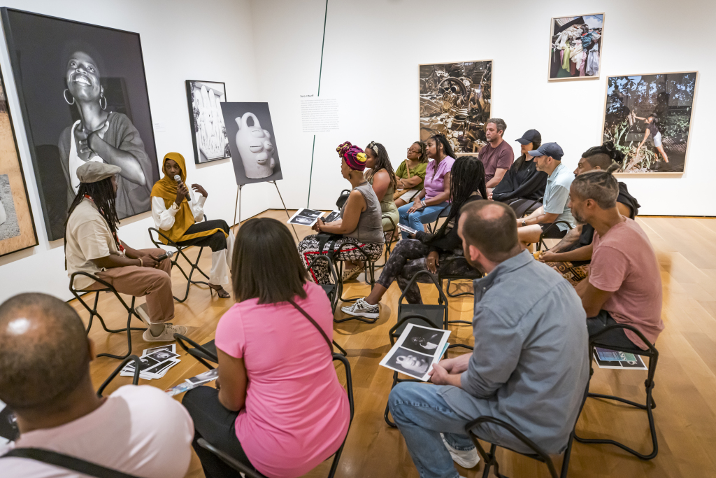 Two individuals having a conversation in a gallery in front of an audience.
