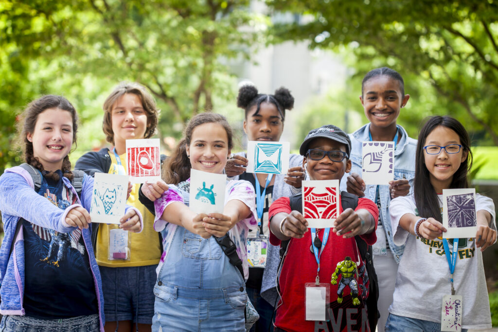 Group of adolescents showing artwork to camera