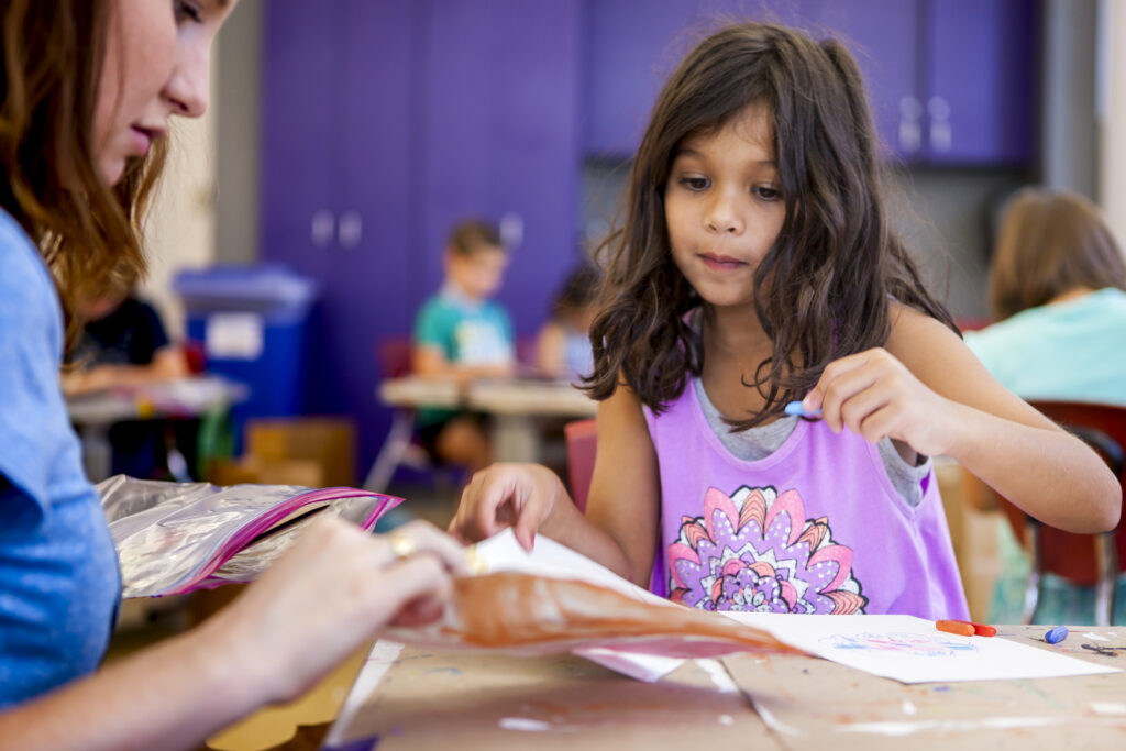 girl with dark hair shows a drawing to an art teacher at the High Museum Summer camp.
