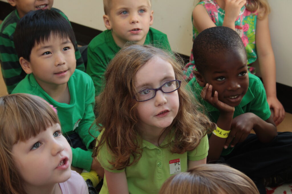 close up of a group of children of all colors and ethnicities looking up.