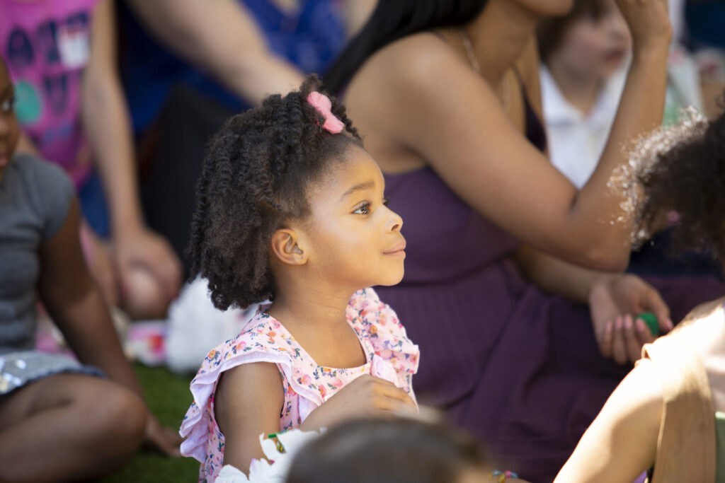 Closeup of a young girl's face in a crowd enjoying a performance.