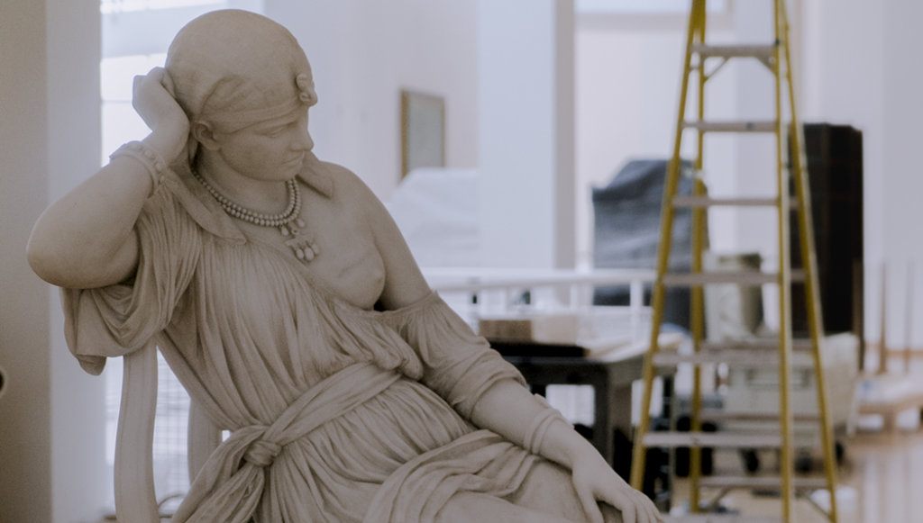Photo of a marble statue of Cleopatra sitting amongst ladders as it waits to be placed in a new location.